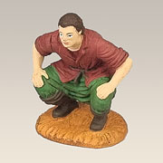Hockender Caganer mit rotem Hemd und grüner Hose